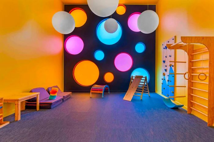 An Airbnb home listed under the Play category features a vibrant game room complete with a slide, climbing wall, and cushioned seating.