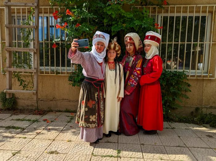 Aidai Asangulova and her family take a selfie, proudly dressed in traditional Kyrgyz attire.