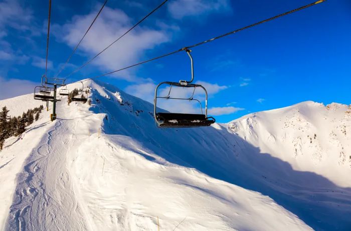 An empty chairlift gliding above a snow-covered mountain