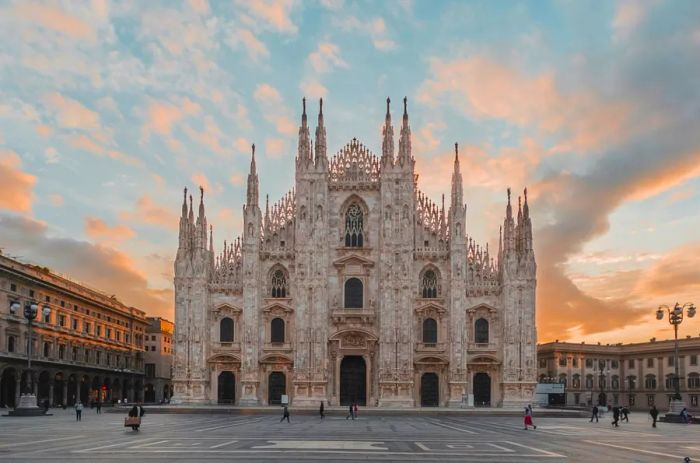 A stunning view of the Duomo's facade in Milan's city center at sunrise, showcasing its many spires and detailed carvings.