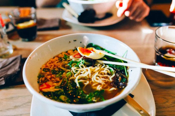 Close-up of a bowl of ramen featuring a soft-boiled egg and chopsticks