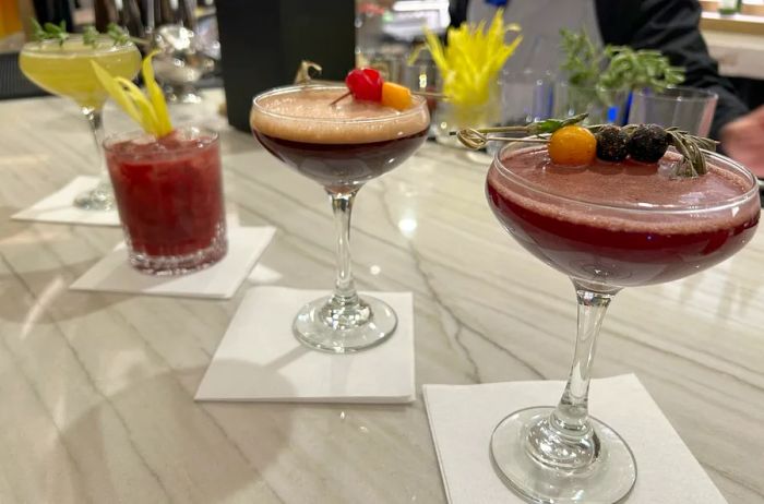 four distinct cocktails in various glasses atop a white marble bar