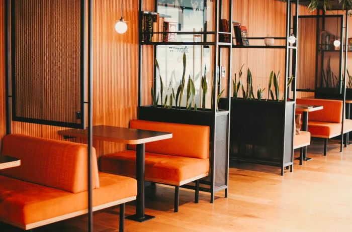 A cluster of four rust-orange booths separated by tall, linear bookshelves in a WeWork coworking space located in Mexico City, Mexico.