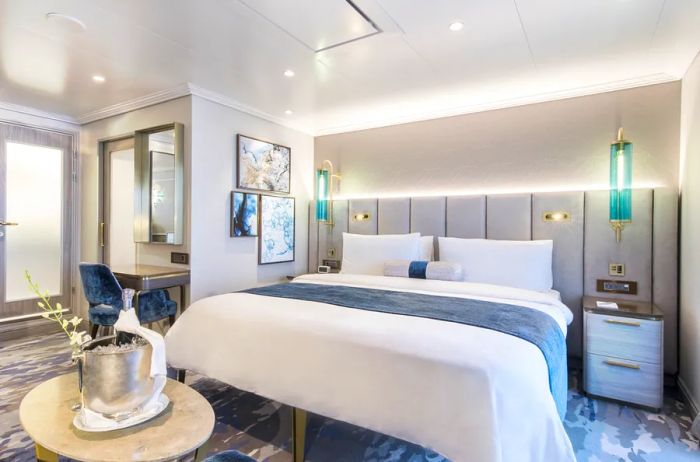 Image showcasing a luxurious bed, desk, and nightstands adorned in blue and gray accents within a veranda suite on a Crystal ocean ship