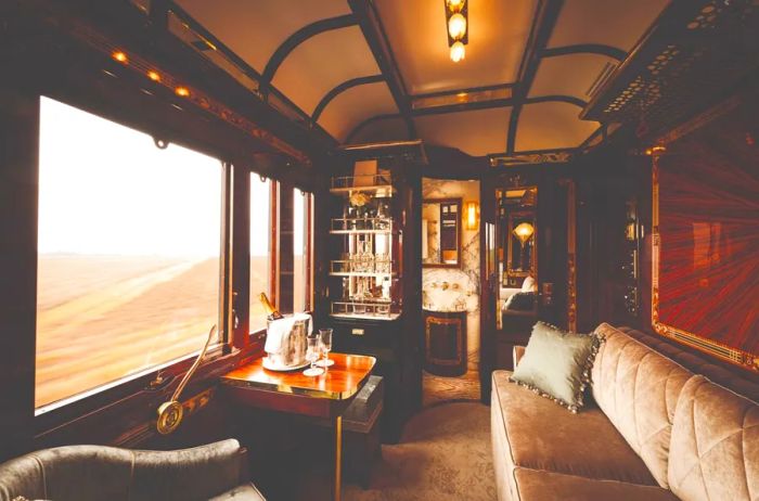 Paris Suite on the Venice Simplon–Orient-Express, showcasing a beige sofa with a view through a large window