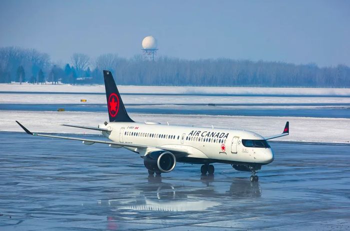 An Air Canada aircraft on a gleaming tarmac in Montreal, with snow in the background.