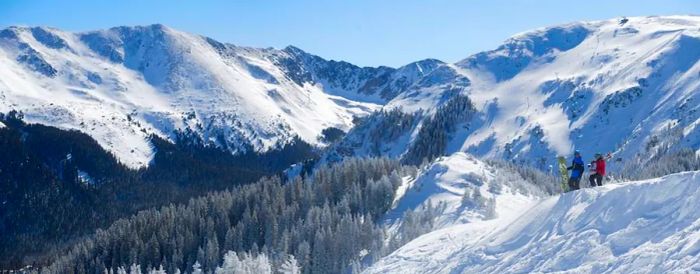 Two skiers admiring the breathtaking vistas of Taos Ski Valley.