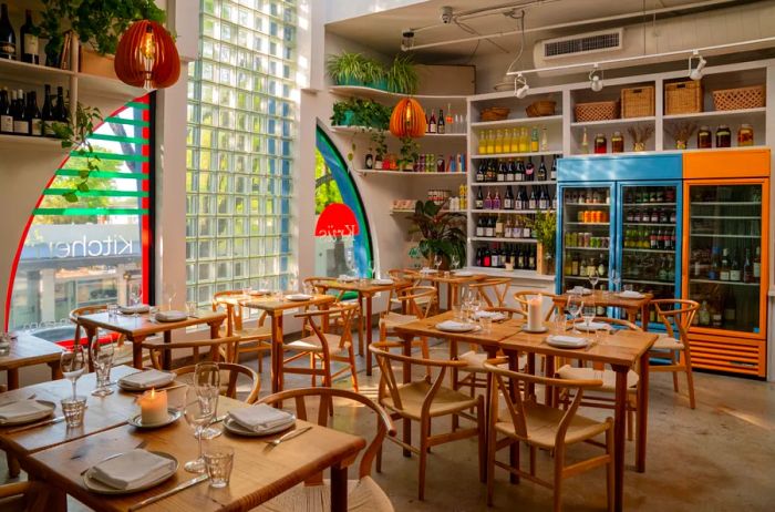 Inside view of Krüs Kitchen in Miami featuring wooden tables, chairs, and vibrant decor