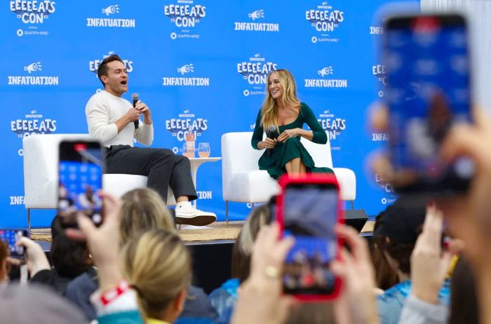 Award-winning actor, producer, and entrepreneur Sarah Jessica Parker converses with Infatuation editorial lead Brant Cox at the Infatuation's EEEEEATSCON New York; both seated on large white chairs on stage.