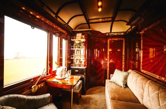 Interior of a Belmond guest room featuring a beige sofa and wooden writing desk facing a window