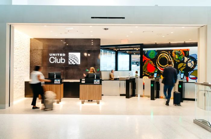 The entrance to the United lounge at Newark Airport's Terminal A features a few travelers walking past a colorful abstract painting.