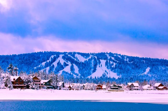 Big Bear in winter showcases snow-draped lodges, mountains blanketed in snow, and evergreens standing tall in the background.