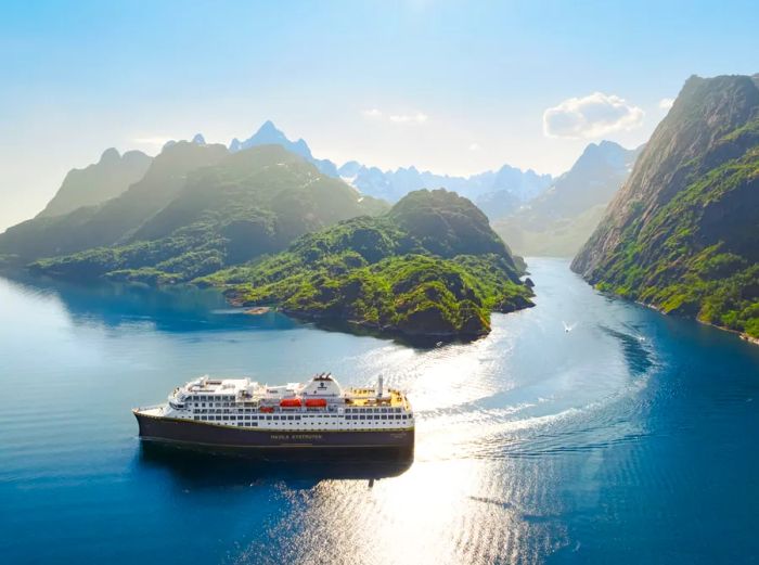A Havila cruise ship navigating among rugged green islands