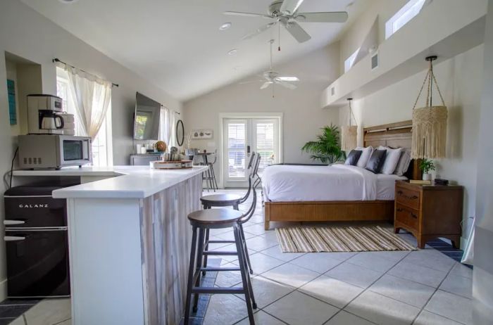 Studio apartment Airbnb featuring a central bed and a pristine white decor scheme