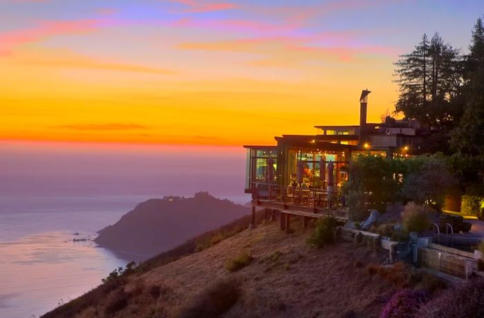 Post Ranch Inn features floor-to-ceiling windows offering breathtaking views of the Pacific Ocean at sunset from its cliffside location.