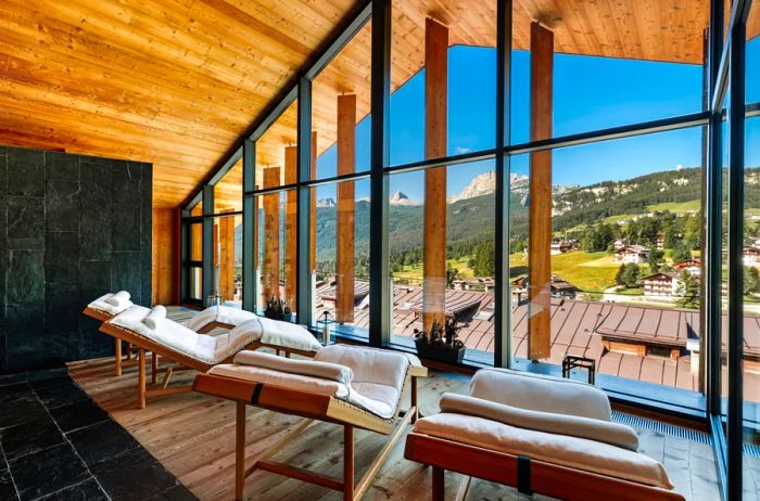 The lounge area at Hotel de Len features wooden finishes and offers views of the stunning Dolomite mountains.