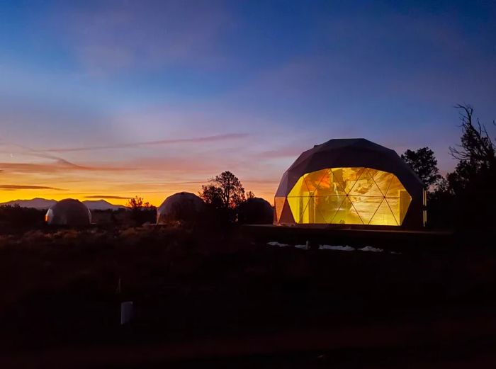 A scenic view of several Clear Sky Resorts globe rooms at dusk, with one room illuminated from within.