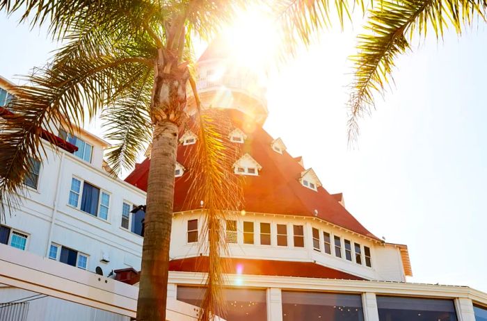 The sun gleams from behind the rounded, red-topped roof of Hotel del Coronado