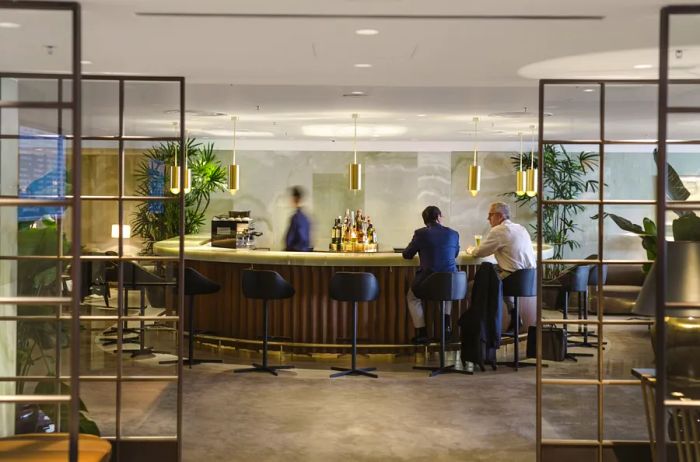 Two business travelers enjoying drinks at the semi-circular bar in Cathay Pacific's Pier Lounge in Hong Kong