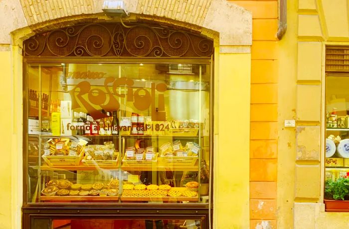 The window display at Antico Forno Roscioli showcases an array of pastries on trays just behind the glass.