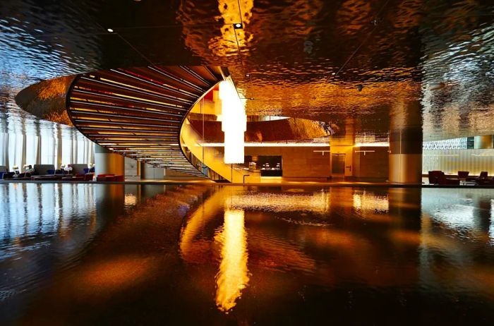 Shiny metallic surfaces and a gracefully curving staircase in Qatar's Al Safwa First Lounge in Doha