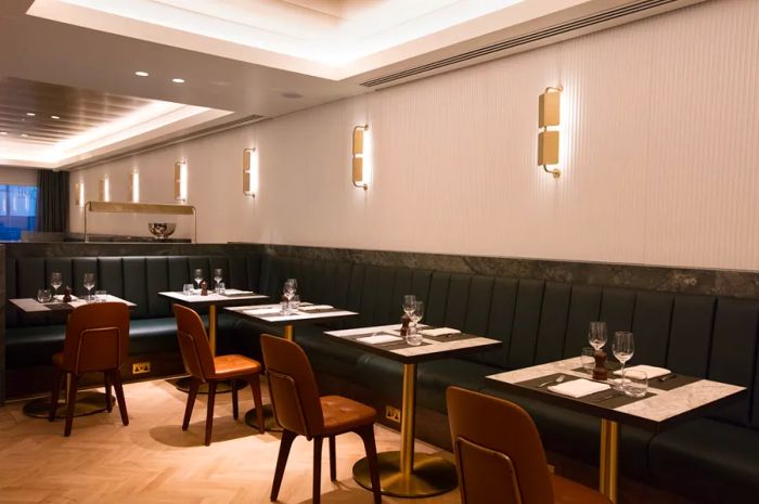 A line of vacant dining tables and chairs along a banquette at the Qantas lounge in London