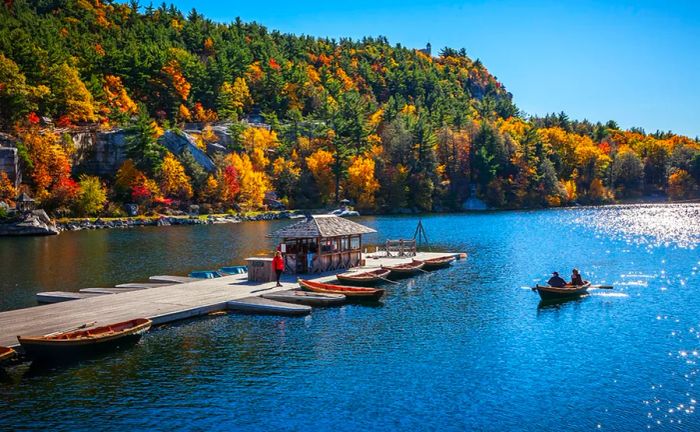 Leisurely boaters enjoying the dock at Mohonk Mountain House, with vibrant autumn foliage in the background.