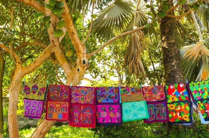 Mola textiles hanging from lines amid trees