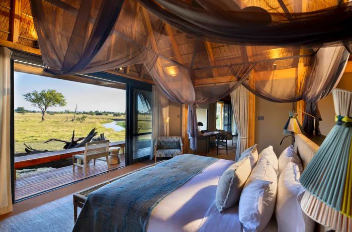 A Tawana bedroom adorned with mosquito nets, featuring a spacious deck that overlooks the Moremi Game Reserve