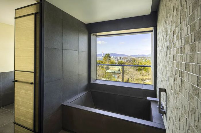 The bathroom in a Deluxe Garden Suite features a spacious black soaking tub positioned beside a window, offering a serene view.