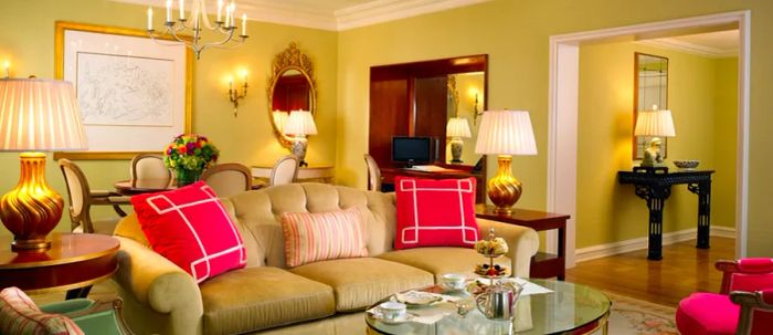 Interior of the California Suite at the Peninsula Beverly Hills, featuring a sofa, illuminated lamps, and large pink cushions