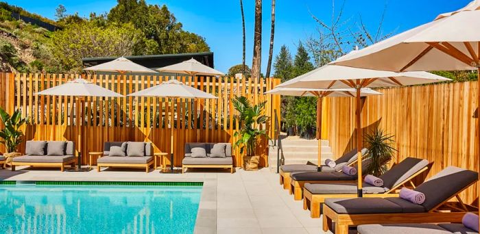 Poolside at Hotel June in Malibu featuring lounge chairs and a wooden fence.