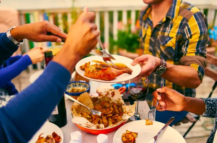 A small group enjoying dinner outdoors, accompanied by red wine