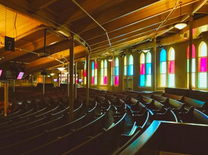 Curved seating arrangements framed by vibrant stained-glass arched windows