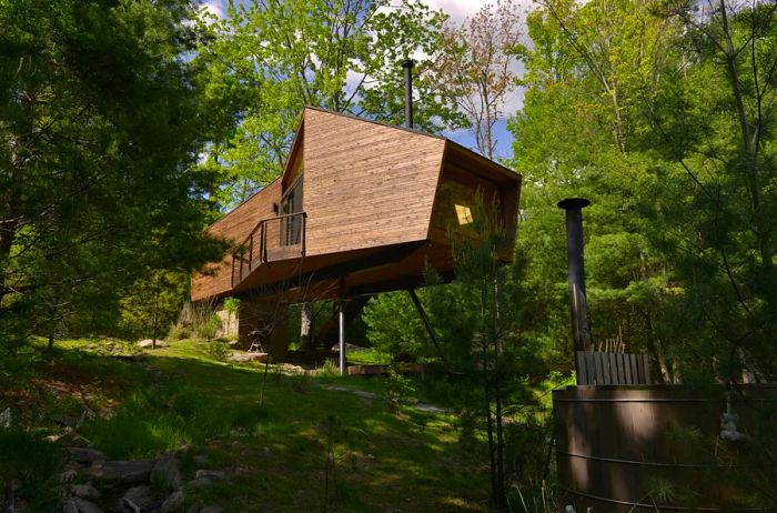 Contemporary tree house in the woods with a wood-fired hot tub in the foreground