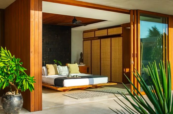 Interior view of a guest room at Cap Karoso, showcasing the outdoor patio through open floor-to-ceiling sliding glass doors.