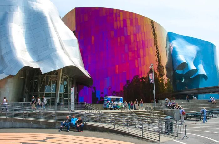 The exterior of the Museum of Pop Culture showcases dynamic silver, vibrant colors, and flowing blue designs crafted by Frank Gehry.