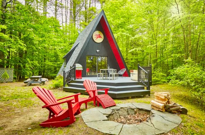 Gray A-frame cabin accented with red trim and two Adirondack chairs in Jamaica, Vermont