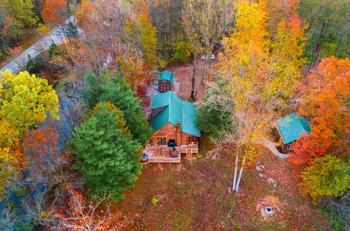 Bird's-eye view of cabins with green roofs nestled in autumn foliage