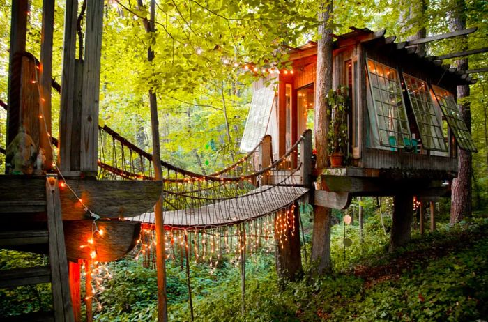 Enchanting rustic tree house cabin adorned with fairy lights and a charming bridge