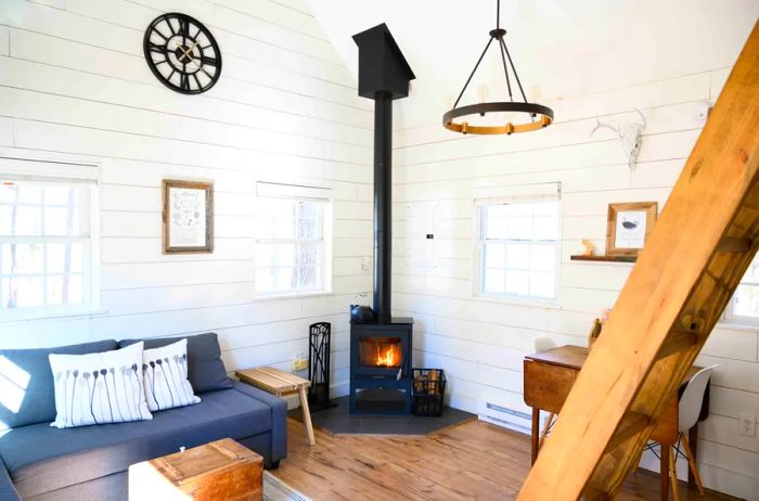 Cozy living room with white walls, small windows, and a wood-burning stove