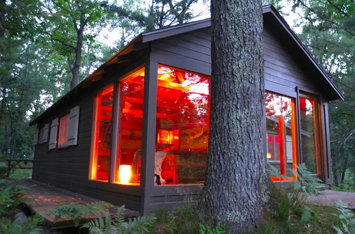 Twilight view of a glass-walled cabin in Michigan