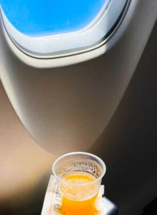 Imagine a glass of orange juice placed next to an airplane window.