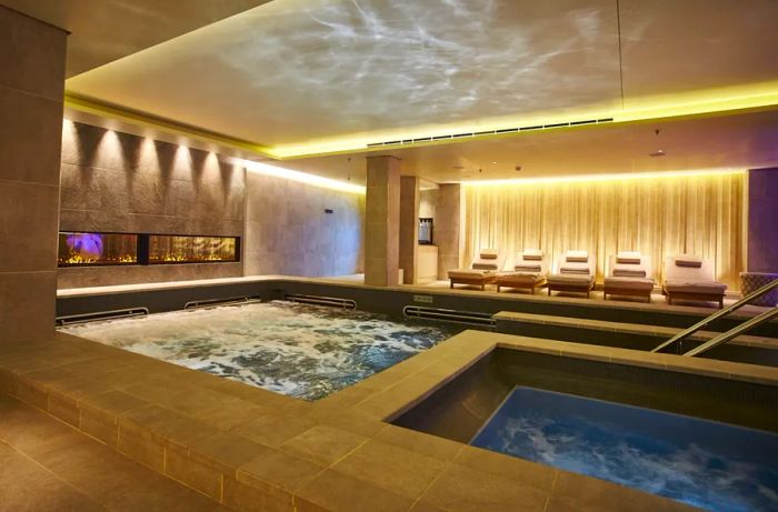 A view of two rectangular indoor pools at the spa on Viking Ocean Cruises, with a row of white lounge chairs in the background