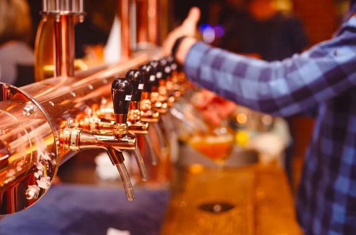 A row of gleaming copper beer taps behind the bar at a pub in Ireland, United Kingdom.