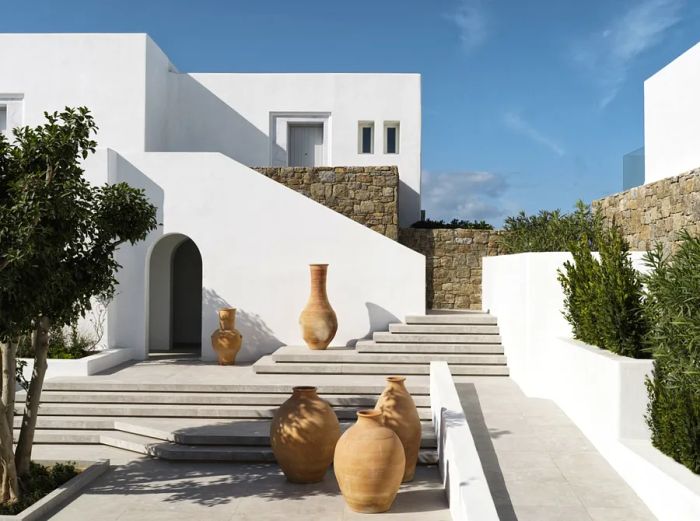 Large clay pots adorn the steps and white structures of DEOS Mykonos in Mykonos town.