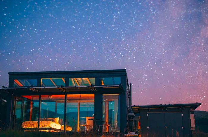 Rectangular glass-walled cottage at night in New Zealand