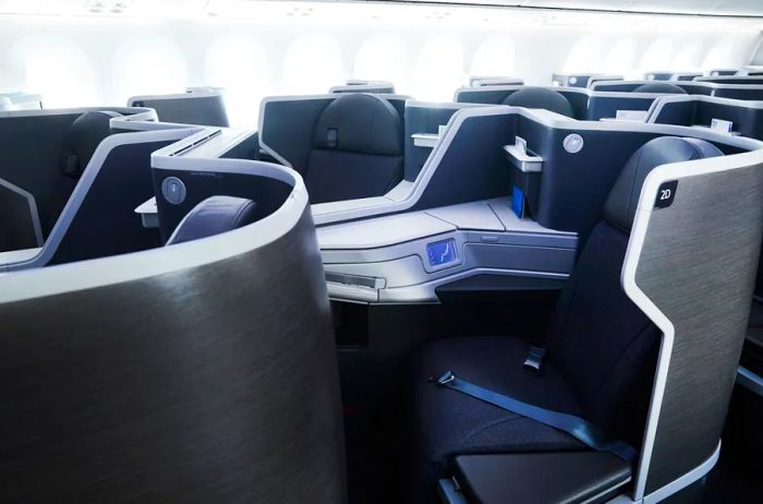 A glimpse of the business class seating on American Airlines reveals shades of grey and blue, featuring partial dividers between the reclining seats.