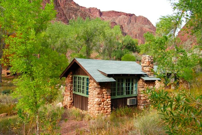 A wooden and stone house nestled among trees and canyons.