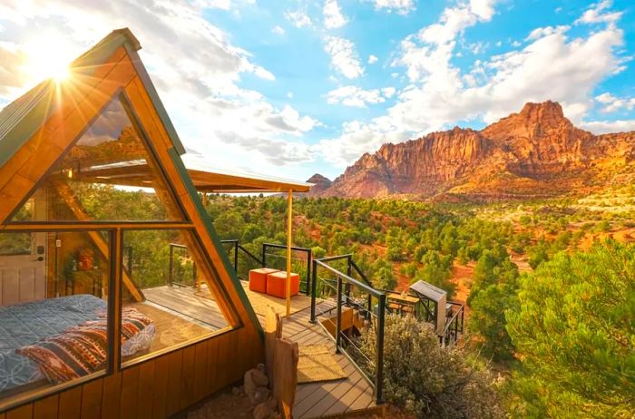 A-frame cabin nestled among trees and red rock formations under a clear blue sky